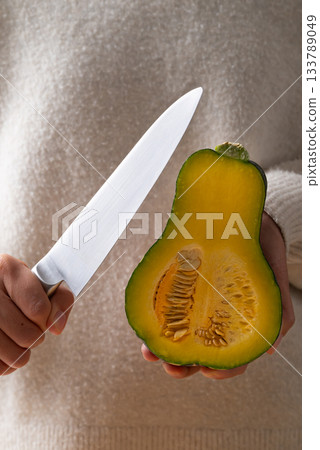 Hand holding kitchen knife and green butternut squash, Homemade cooking 133789049