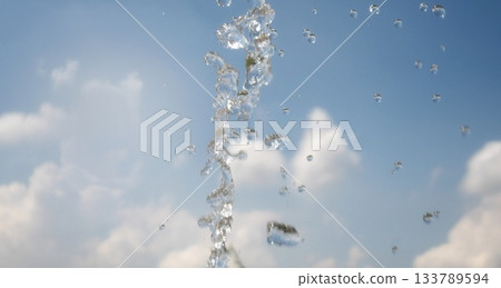 Splashing water against the background of blue sky and white clouds_flowing water_close-up 133789594