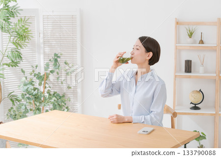 A woman with green juice and a smartphone 133790088