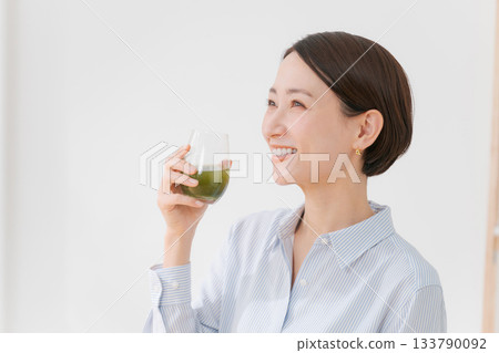 一位女士手捧綠色果汁和一部智慧型手機 133790092