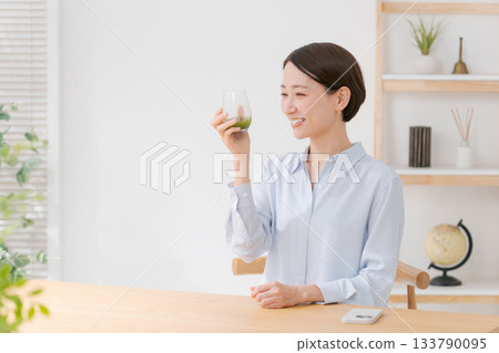 一位女士手捧綠色果汁和一部智慧型手機 133790095