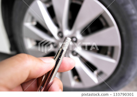 Close-up of a hand holding a tire pressure gauge displaying a PSI pressure range Close-up of a hand holding a tire pressure gauge displaying a PSI pressure range 133790301