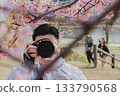 A young man taking a photo of Kawazu cherry blossoms 133790568
