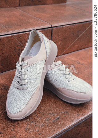 Fresh beige leather sneakers without brand marks displayed. For design templates online shops and sustainability-themed marketing. Clean blank sneakers 133790624