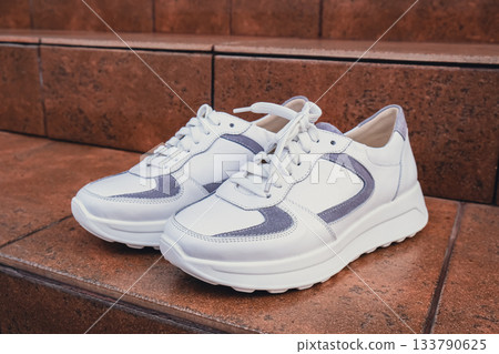 Fresh white leather sneakers without brand marks displayed. For design templates online shops and sustainability-themed marketing. Clean blank sneakers 133790625