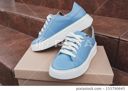 Elegant blue leather womens shoes blank product for branding displayed on recycled cardboard box. New casual female sneakers no-brand footwear e-commerce. No logo product unbranded fashion 133790645