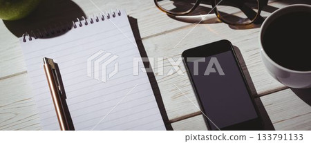 Notepad by smart phone on desk Notepad by smart phone on desk 133791133