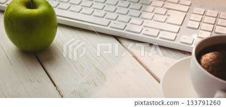 Keyboard with coffee cup and green apple on table 133791260