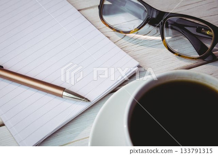 Notepad by reading glasses and coffee on table Notepad by reading glasses and coffee on table 133791315