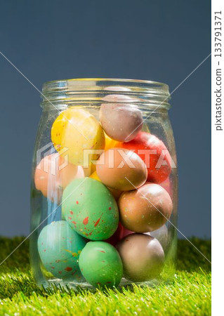 Easter eggs in glass jar on grassy field Easter eggs in glass jar on grassy field 133791371