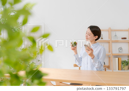 A woman with green juice and a smartphone A woman with green juice and a smartphone 133791797