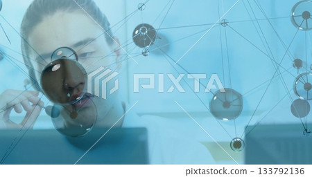 Analyzing data on monitor in white shirt at office desk, with network overlay graphic, copy space 133792136