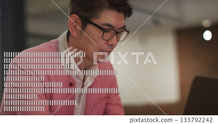 Focusing Asian man wearing pink blazer typing on laptop at modern office desk, with eyeglasses Focusing Asian man wearing pink blazer typing on laptop at modern office desk, with eyeglasses 133792242