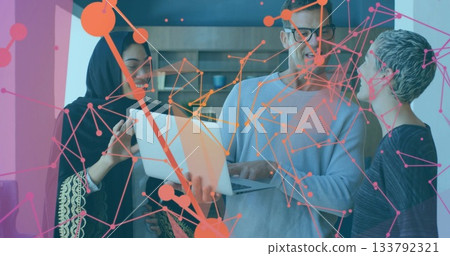 Tech colleagues discussing digital network overlay on silver laptop in office, with wooden shelves 133792321