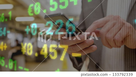 Tapping smartphone screen senior trader tracking currency overlays on trading floor, with suit 133792339