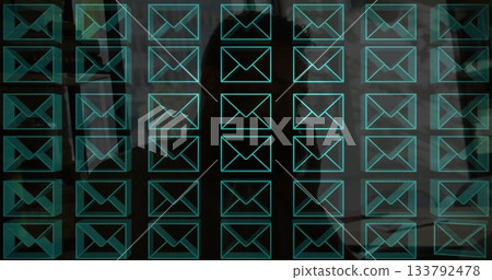 Displaying digital message grid projecting over dim office workspace, with turquoise envelope icons 133792478