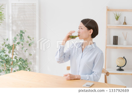A woman drinking bitter green juice A woman drinking bitter green juice 133792689