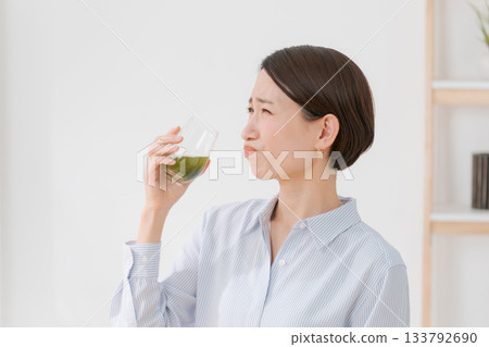 A woman drinking bitter green juice A woman drinking bitter green juice 133792690