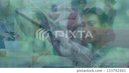 Professional holding tablet and smiling with coworkers at conference table showing stock tickers 133792881