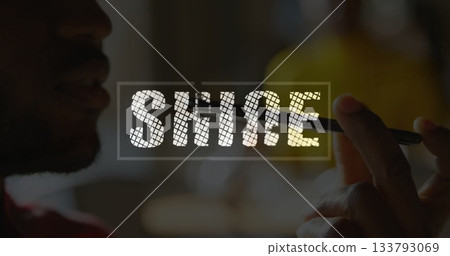 Holding stylus, side-profile silhouette man drawing SHINE overlay on tablet in studio, red shirt 133793069