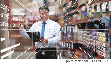Warehouse manager in suit holding tablet inspecting shelves in warehouse aisle, with data panels 133793124