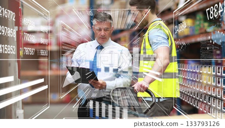Reviewing digital overlay, tie-clad manager and vested worker using pallet jack in warehouse aisle 133793126