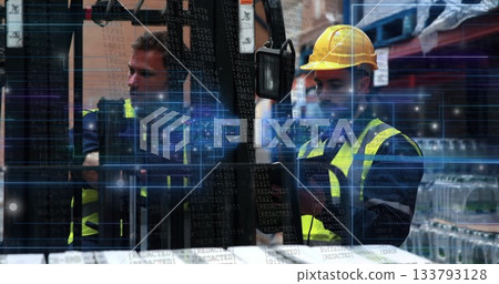 Workers wearing vests and hard hat operating forklift controls in warehouse, with digital overlay 133793128