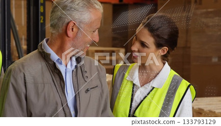 Discussing supervisor and safety inspector reviewing goods in warehouse, with pallets and vest Discussing supervisor and safety inspector reviewing goods in warehouse, with pallets and vest 133793129