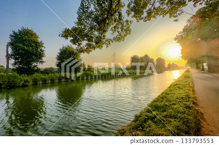 Serene sunset by waterway, Peaceful canal scene with warm reflections Serene sunset by waterway, Peaceful canal scene with warm reflections 133793553