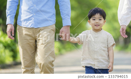 一家三口沿著綠樹成蔭的小路散步。 133794015