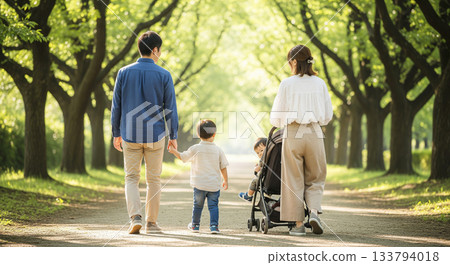 一家四口沿著綠樹成蔭的小路行走，背影清晰可見。 133794018