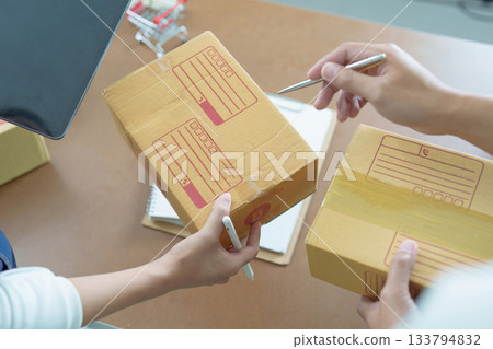 Small Business. Entrepreneurs discussing shipping details while preparing packages. 133794832