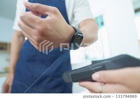 Small Business. Entrepreneur using smartwatch for contactless payment in a modern cafe. Small Business. Entrepreneur using smartwatch for contactless payment in a modern cafe. 133794869