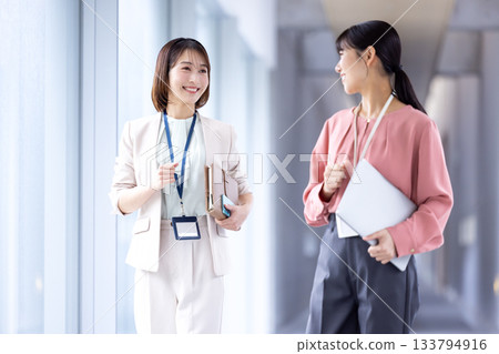 Business: Women walking down the aisle while having a conversation 133794916