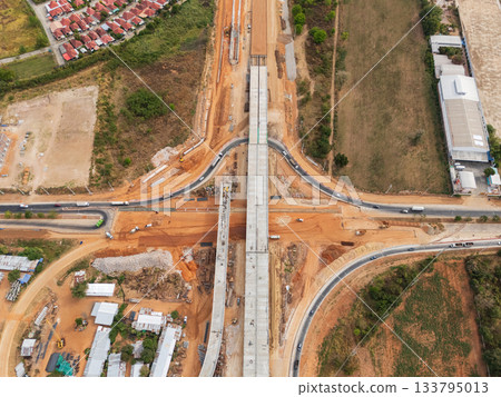 The construction site before the construction of the concrete bridge over the intersection by crane workers, tractors, and backhoes 133795013