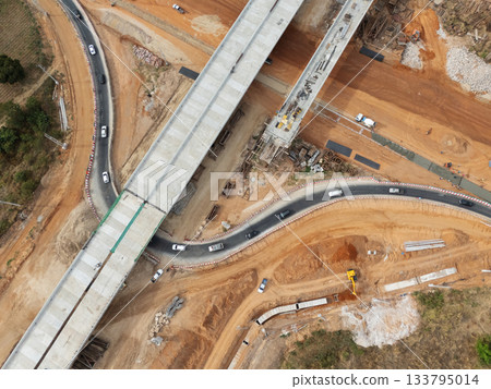 The construction site before the construction of the concrete bridge over the intersection by crane workers, tractors, and backhoes The construction site before the construction of the concrete bridge over the intersection by crane workers, tractors, and backhoes 133795014
