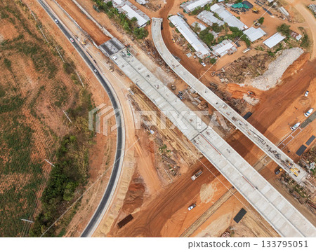 The construction site before the construction of the concrete bridge over the intersection by crane workers, tractors, and backhoes 133795051