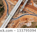 The construction site before the construction of the concrete bridge over the intersection by crane workers, tractors, and backhoes 133795094