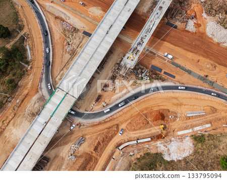 The construction site before the construction of the concrete bridge over the intersection by crane workers, tractors, and backhoes 133795094