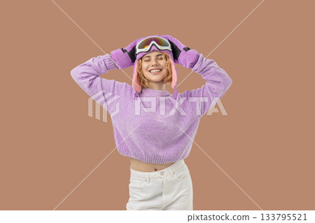Woman poses cheerfully in winter ski gear with goggles Woman poses cheerfully in winter ski gear with goggles 133795521