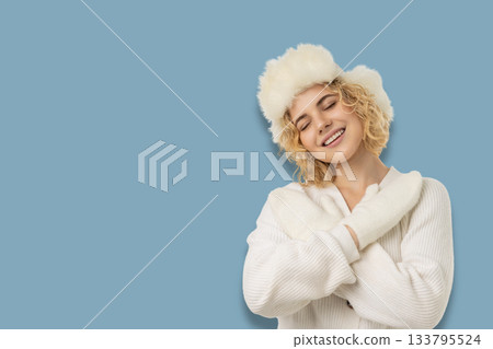 Woman smiling while wearing a white sweater and fluffy hat Woman smiling while wearing a white sweater and fluffy hat 133795524