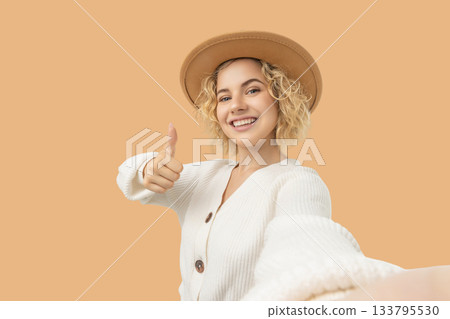 Young woman with curly blonde hair wearing a beige hat 133795530