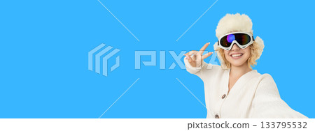 Woman in ski gear smiles and shows peace sign 133795532