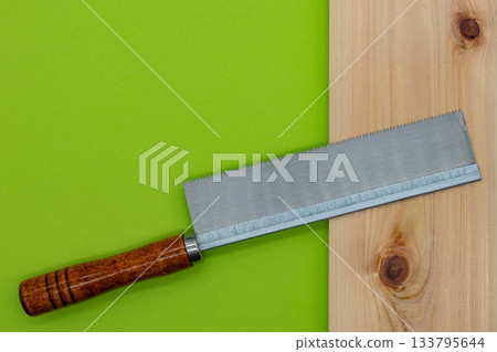 Saw and cypress board on yellow-green background_DIY, tools, woodworking image Saw and cypress board on yellow-green background_DIY, tools, woodworking image 133795644