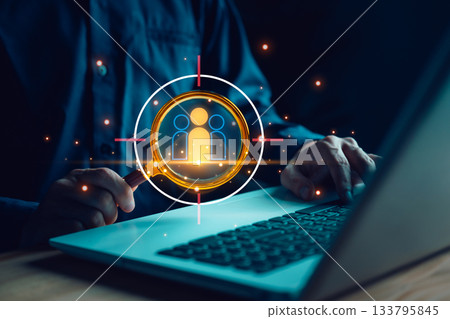 Recruiter using magnifying glass targeting best candidates on laptop, symbolizing HR analytics, talent acquisition, employee search, or workforce optimization in digital recruitment. 133795845