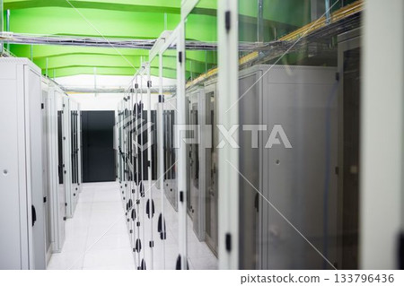 Server rack cabinets are lining aisle in flat design, featuring green beams and white floor tiles Server rack cabinets are lining aisle in flat design, featuring green beams and white floor tiles 133796436