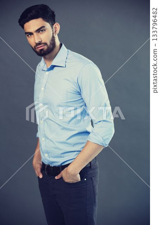 Portrait of young man standing against gray background 133796482