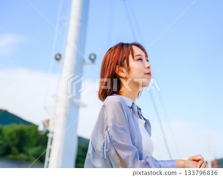 年輕女子乘船仰望藍天，夏季旅遊之旅 133796836