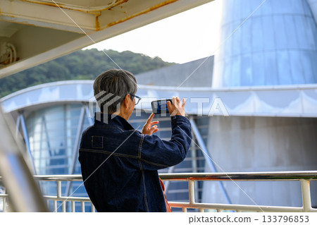 A senior woman taking pictures of the scenery with her smartphone on the ferry heading to Oki Island A senior woman taking pictures of the scenery with her smartphone on the ferry heading to Oki Island 133796853