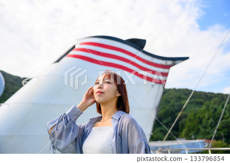 旅行肖像照,一位年輕女子仰望天空,背景是一艘船的煙囪。 旅行肖像照,一位年輕女子仰望天空,背景是一艘船的煙囪。 133796854